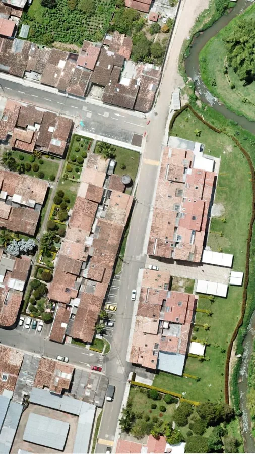 Vista aérea de áreas construidas junto a un corredor hídrico y zonas de vegetación.