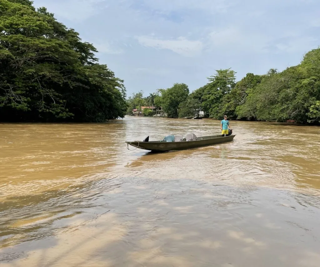 Cauce de aguas turbias con vegetación densa en ambas márgenes, recorrido en bote durante una jornada de campo
