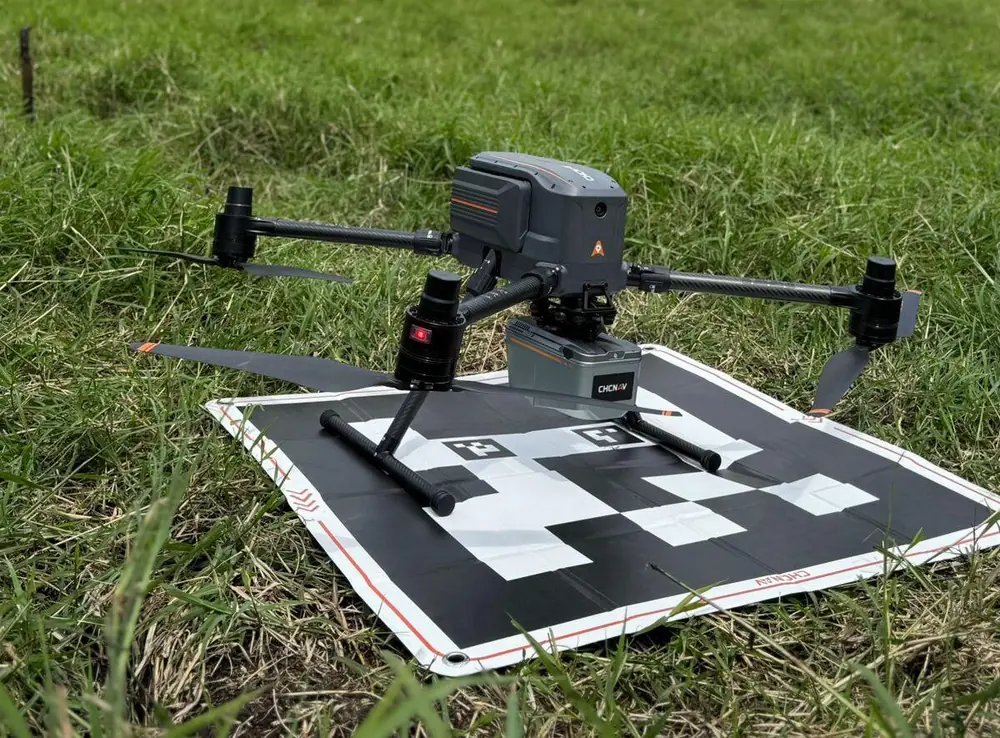 Dron con sensor LiDAR posado sobre su plataforma de despegue, en un potrero, antes del vuelo